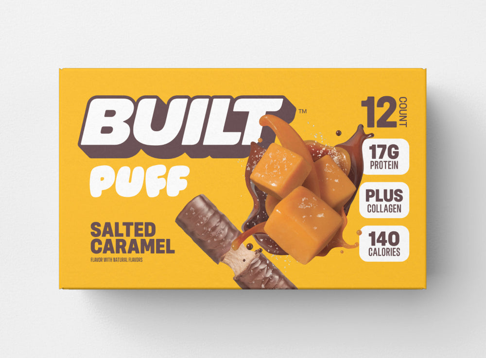 A yellow box of 12 BUILT salted caramel puffs on a white background.