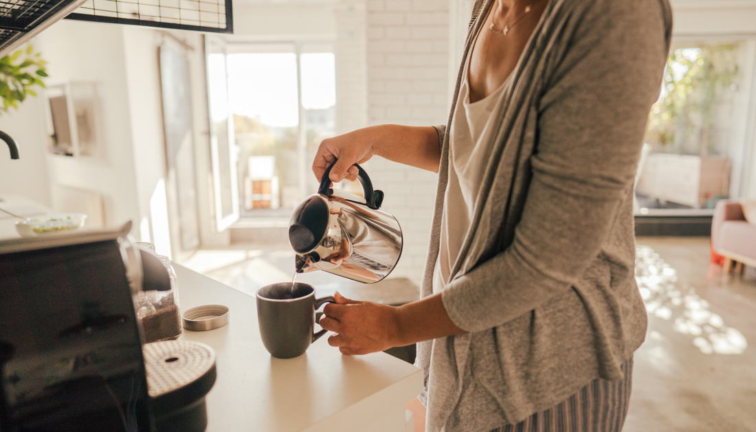 woman standing at the kitchen counter pouring coffee from the pot into a mug
