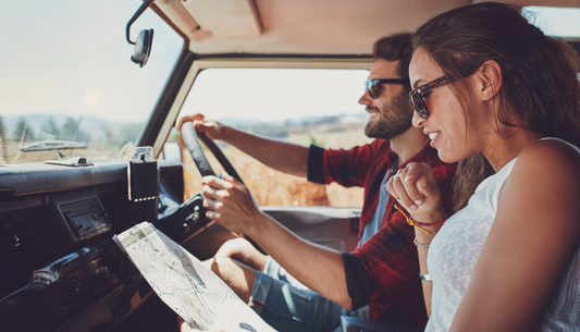 Two people planning a summer road trip in a car with a map