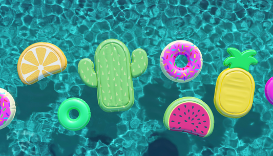 Colorful inflatable pool floats floating in a clear blue swimming pool on a sunny summer day.