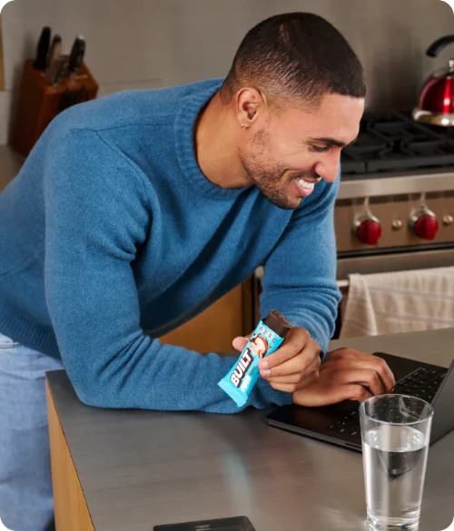 man working on a laptop and eating a BUILT puff